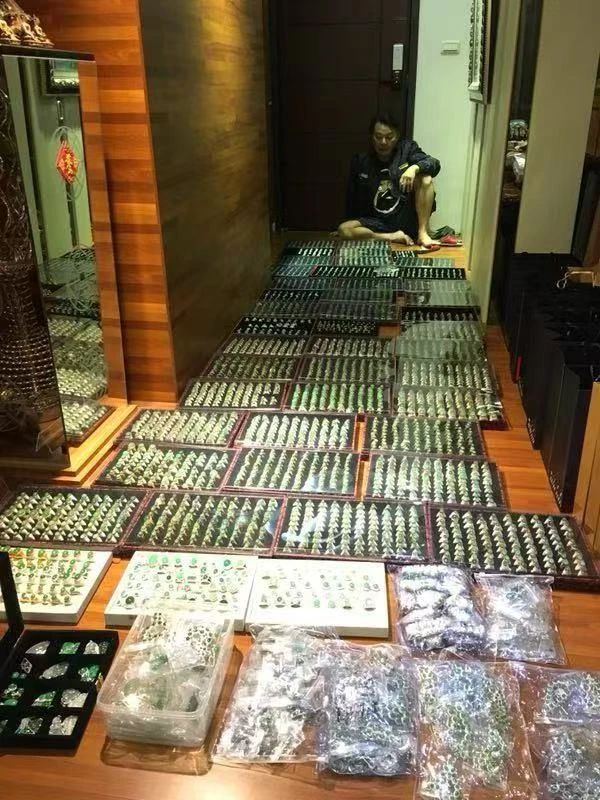 室内の一角に座る人物。前の床に装飾品のトレーが並ぶ。