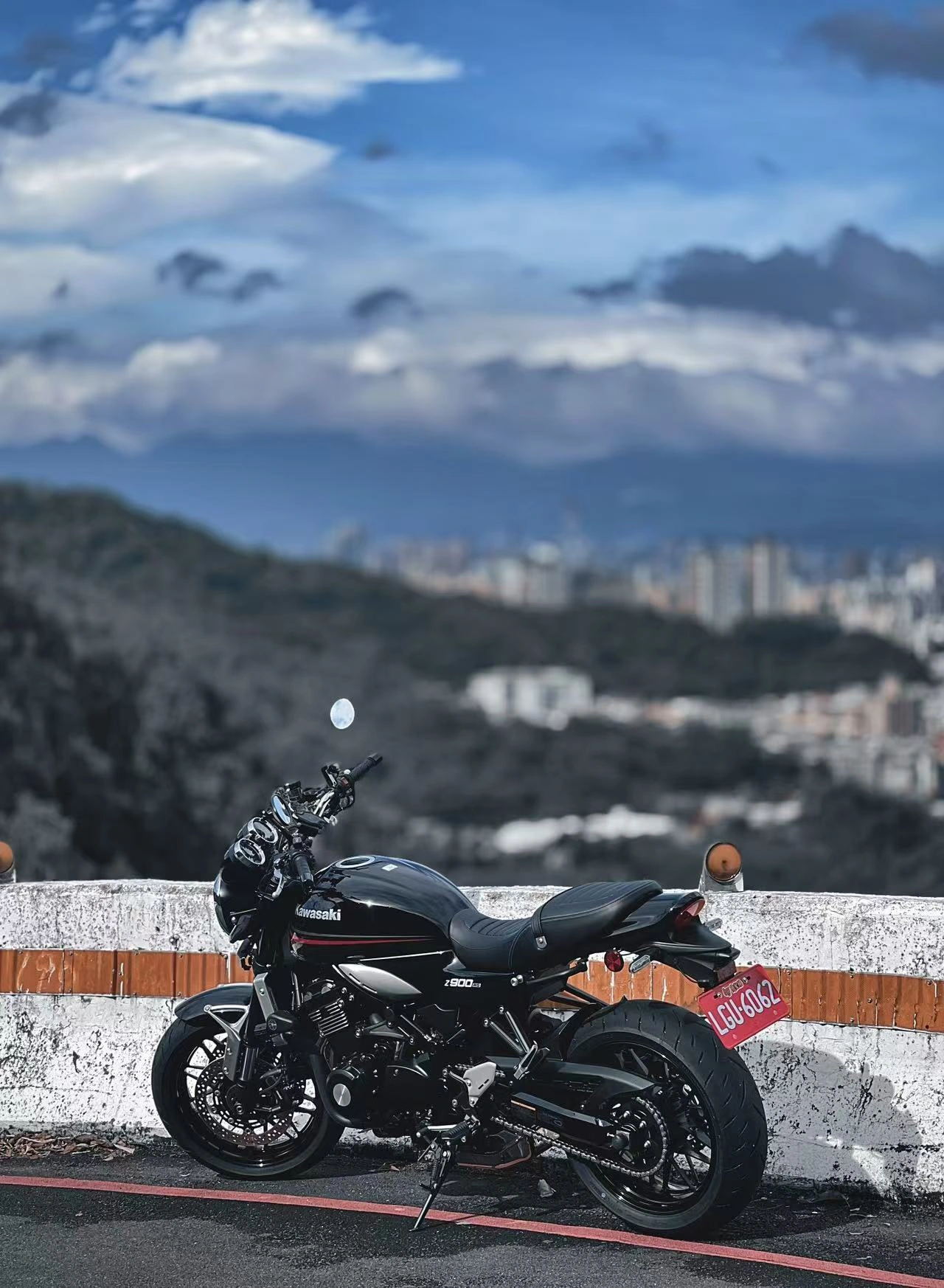 重機停在道路護欄旁，遠方可見山景與城市。